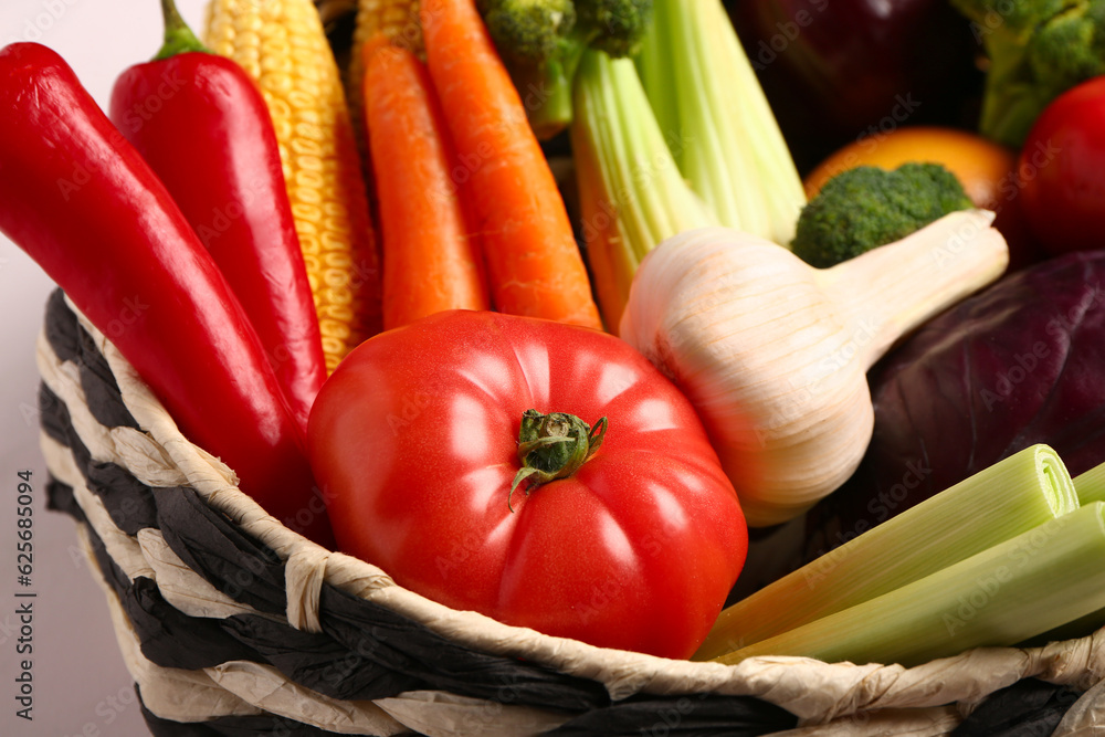 Wicker bowl with different fresh vegetables on white background, closeup