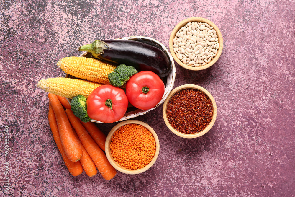 Wicker bowl with different fresh vegetables and cereals on purple background