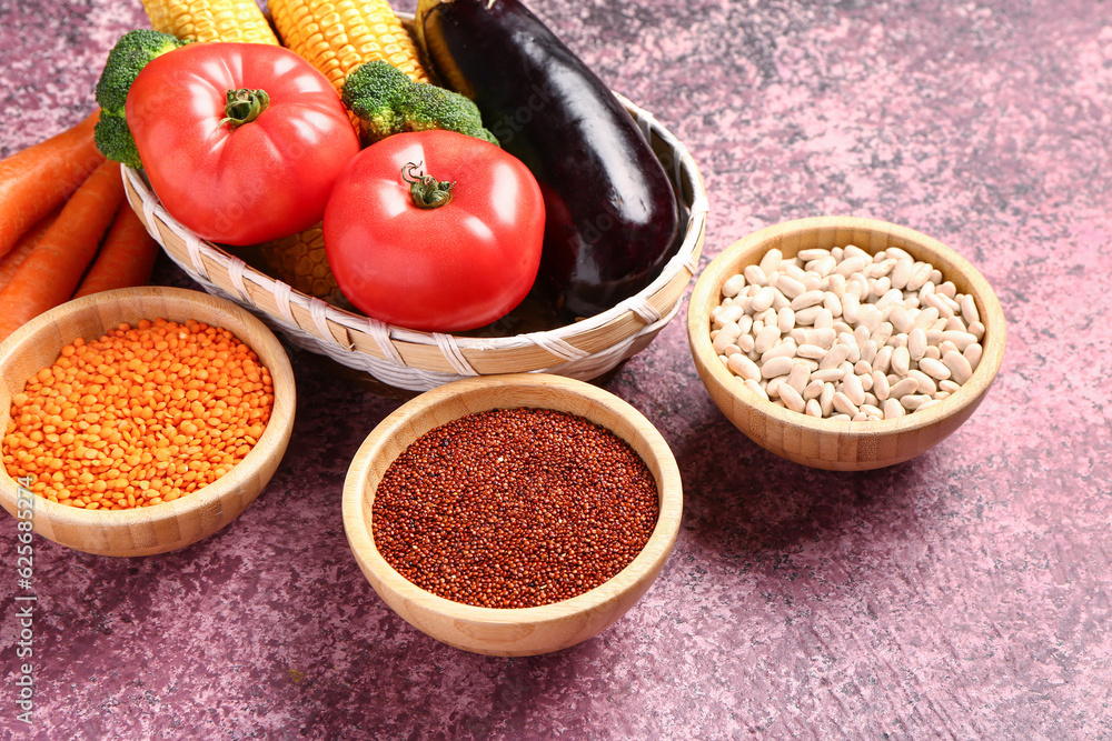 Wicker bowl with different fresh vegetables and cereals on purple background