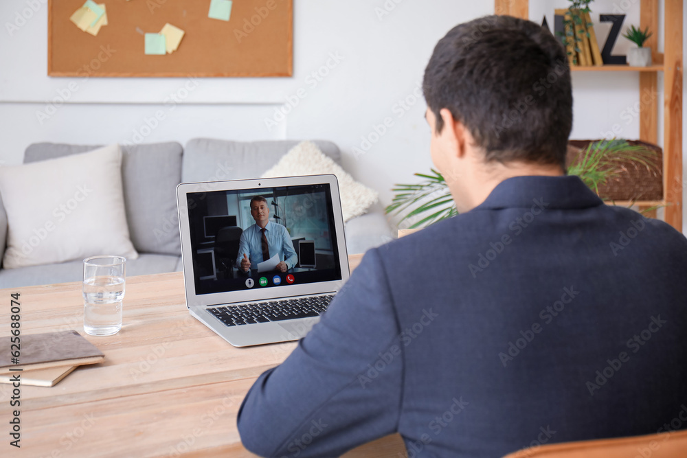 Young man having job interview online at home, back view