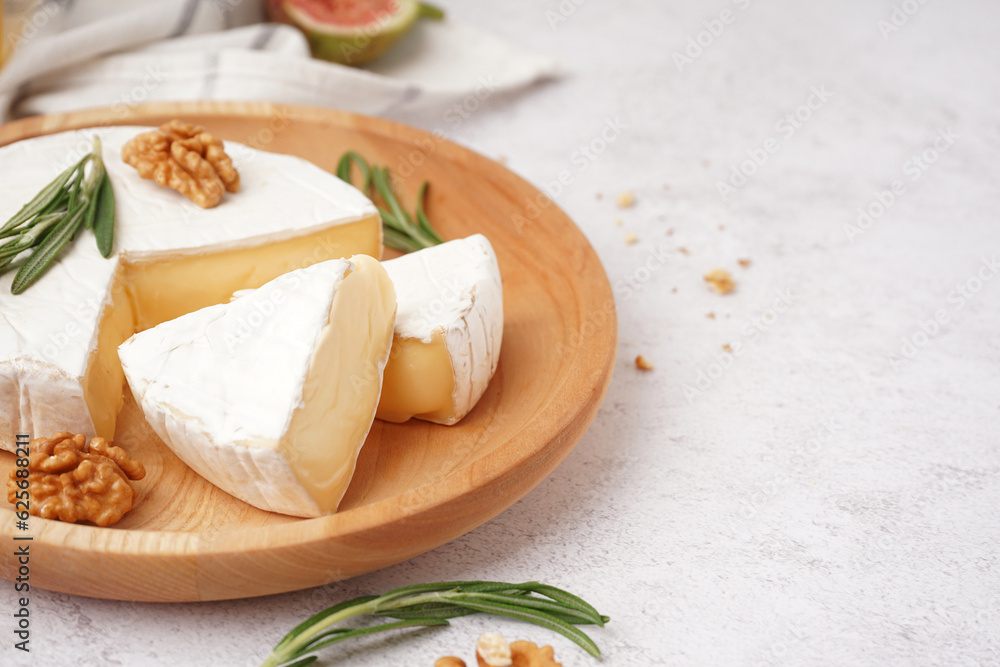 Plate with pieces of tasty Camembert cheese on light background