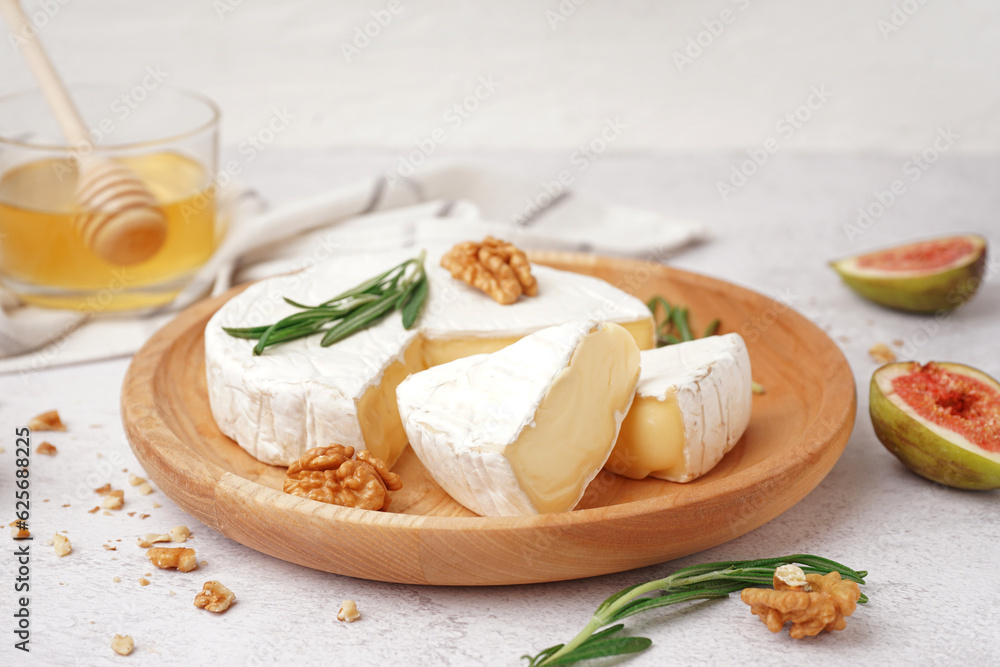 Plate with pieces of tasty Camembert cheese on light background