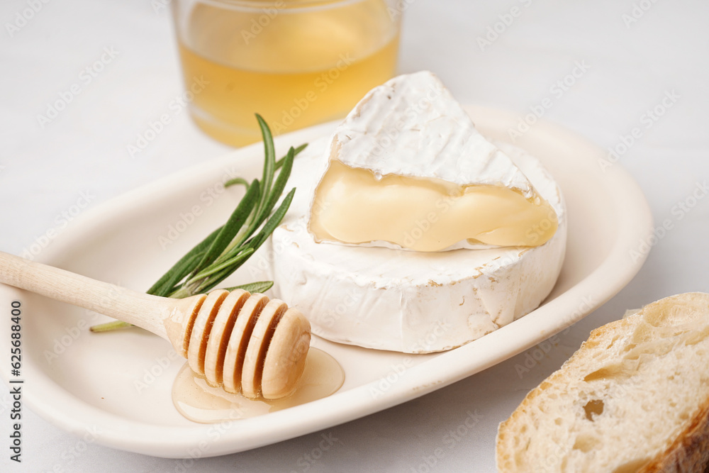 Plate with tasty Camembert cheese on light background