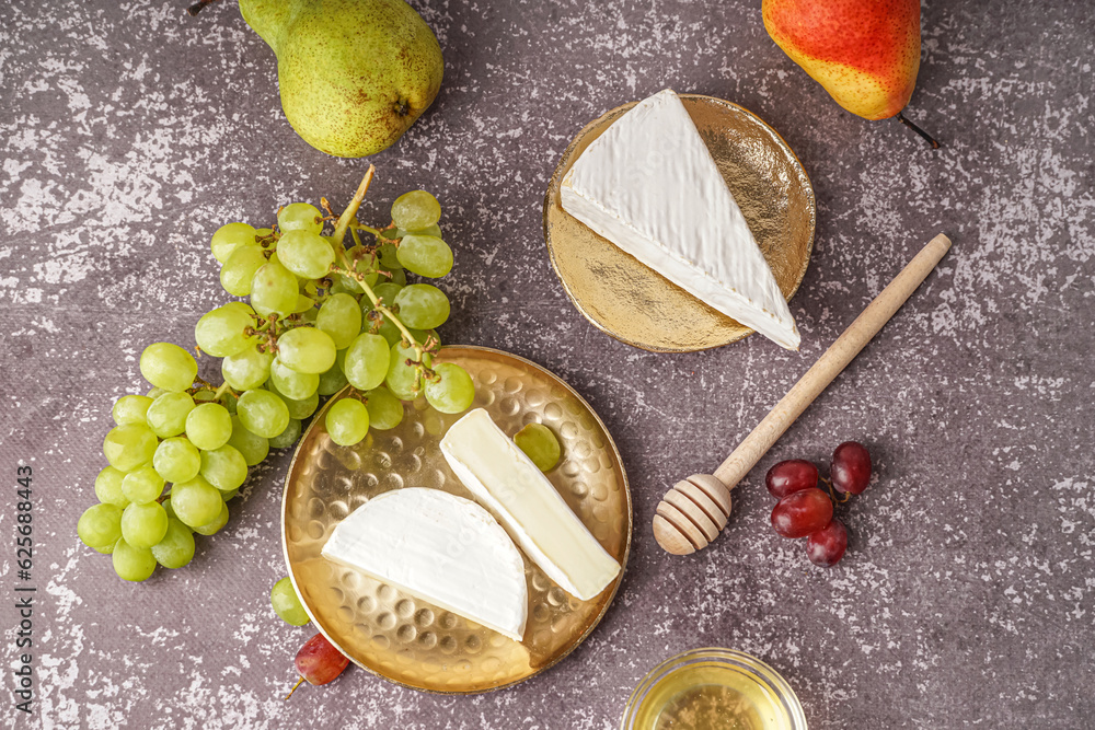 Plates with pieces of tasty Camembert cheese on grey background