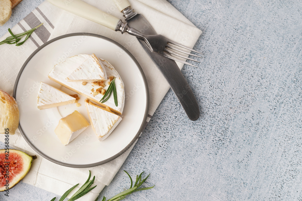 Plate with pieces of tasty Camembert cheese on grey background