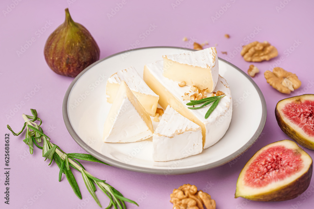 Plate with pieces of tasty Camembert cheese on lilac background