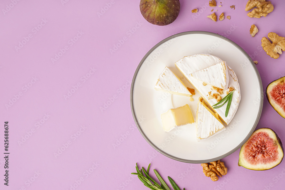 Plate with pieces of tasty Camembert cheese on lilac background