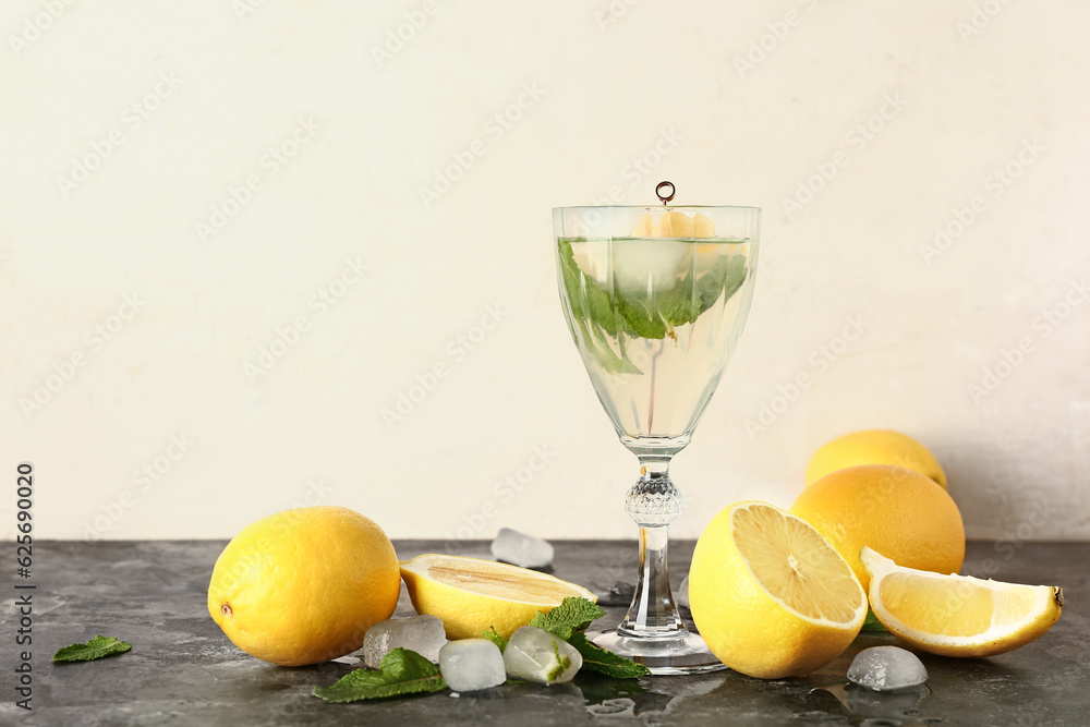 Glass of cold mojito and lemons on dark table