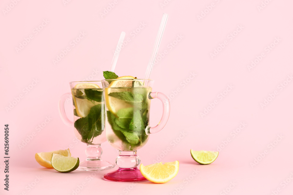 Glasses of cold mojito and citrus fruits on pink background