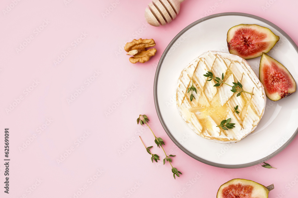 Plate of tasty baked Camembert cheese on pink background