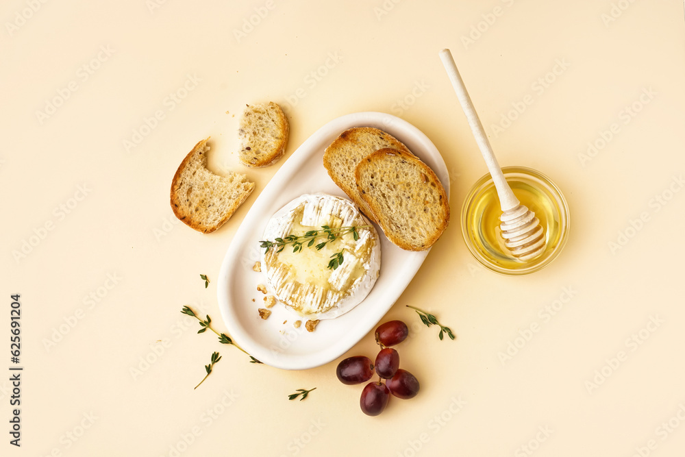 plate of tasty baked Camembert cheese with bread on yellow background