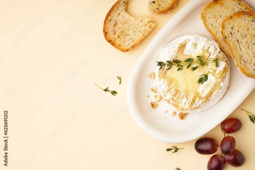 plate of tasty baked Camembert cheese with bread on yellow background