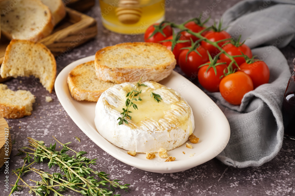 Plate of tasty baked Camembert cheese on grey background