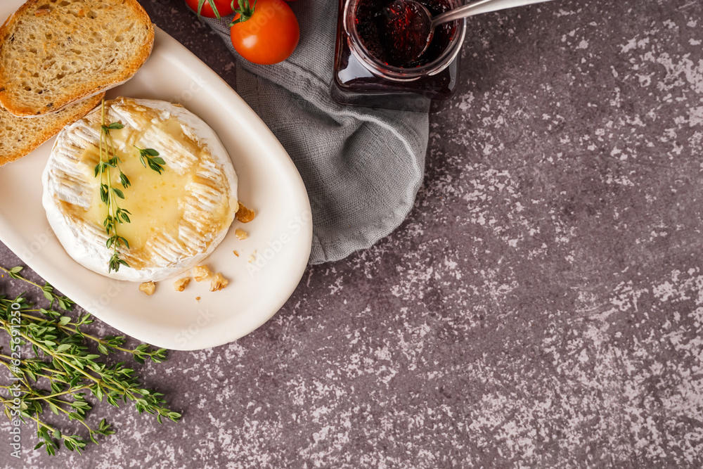 Plate of tasty baked Camembert cheese on grey background