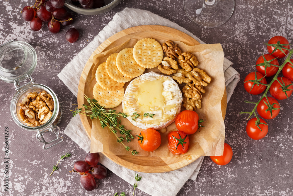 Plate of tasty baked Camembert cheese on grey background