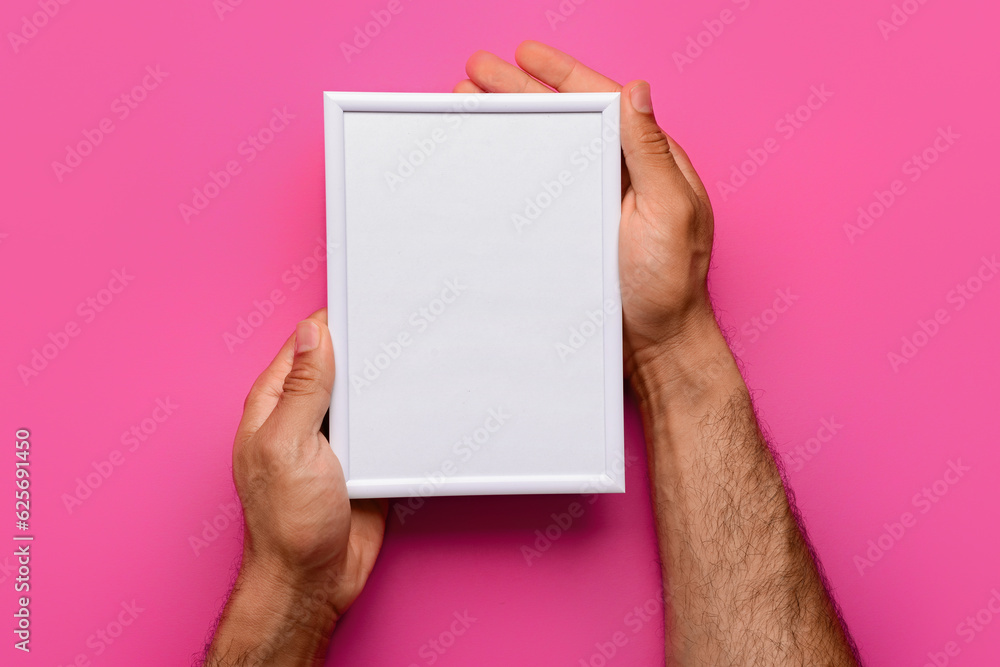 Man holding blank photo frame on pink background