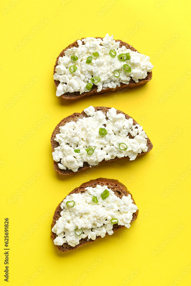 Tasty sandwiches with cottage cheese on yellow background