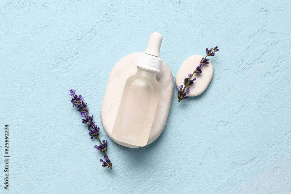 Composition with bottle of essential oil, spa stones and lavender flowers on light background