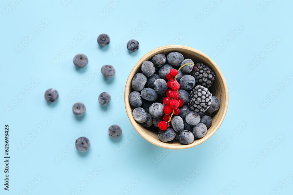 Bowl of frozen berries on blue background