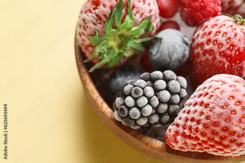 Bowl of frozen berries on yellow background