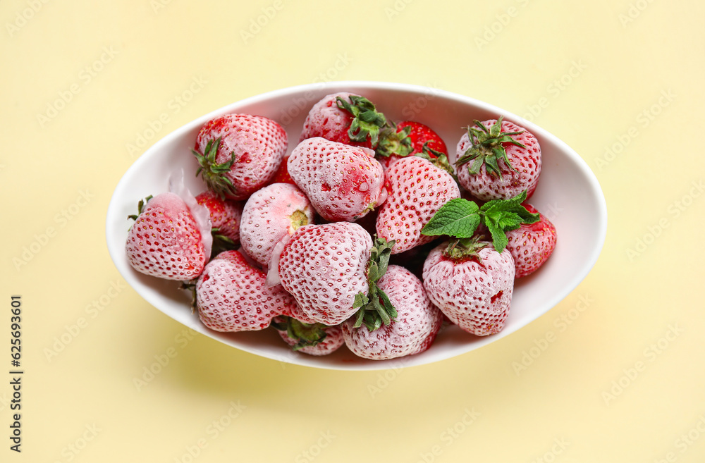 Bowl of frozen strawberry with mint leaves on yellow background