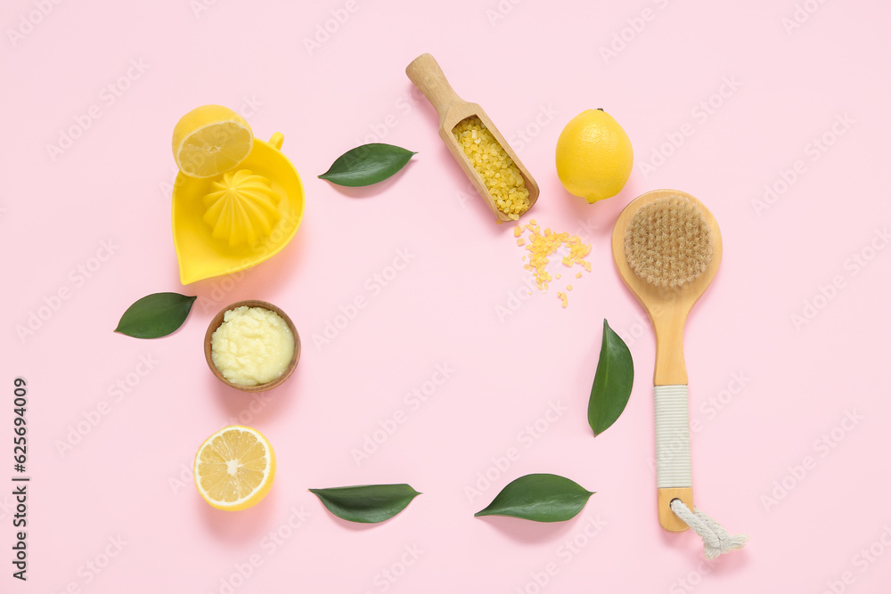 Frame made of lemon body scrub with juicer, sea salt and massage brush on pink background