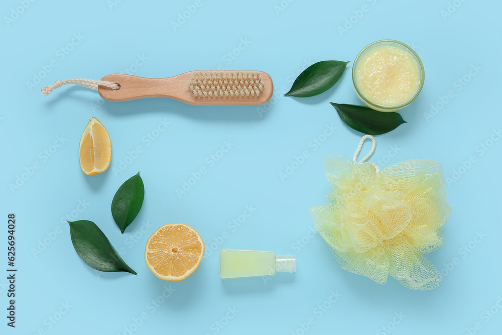 Frame made of bowl of lemon body scrub with bath supplies on blue background