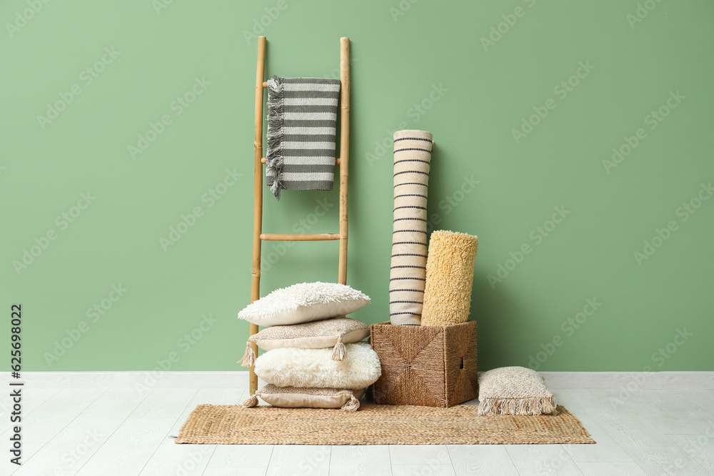 Carpets, cushions and wicker rug near green wall