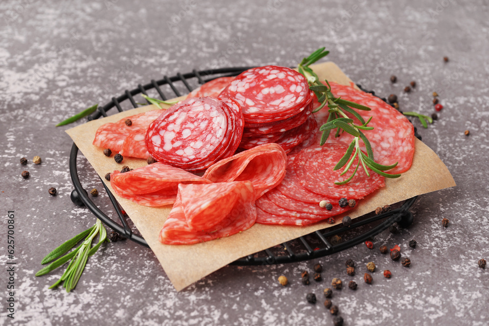 Grid with slices of tasty salami on grey background