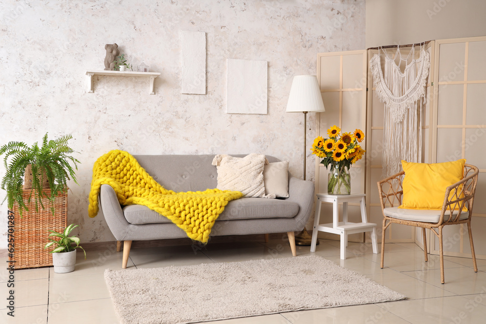 Vase with beautiful sunflowers on table in interior of light living room, closeup