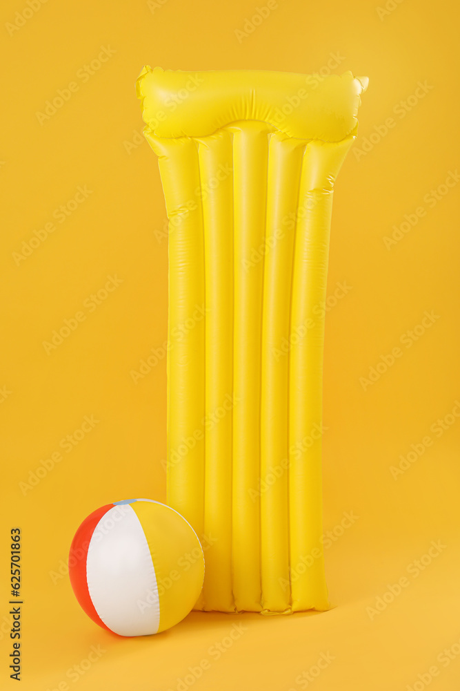 Inflatable mattress with beach ball on yellow background