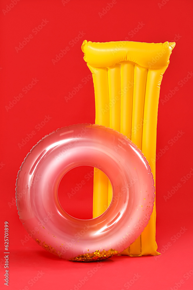 Inflatable mattress and ring on red background