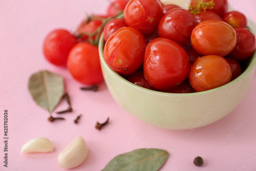 Bowl with canned tomatoes and garlic on pink background