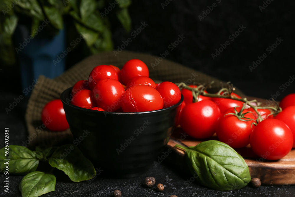 Bowl with canned tomatoes and basil on black background