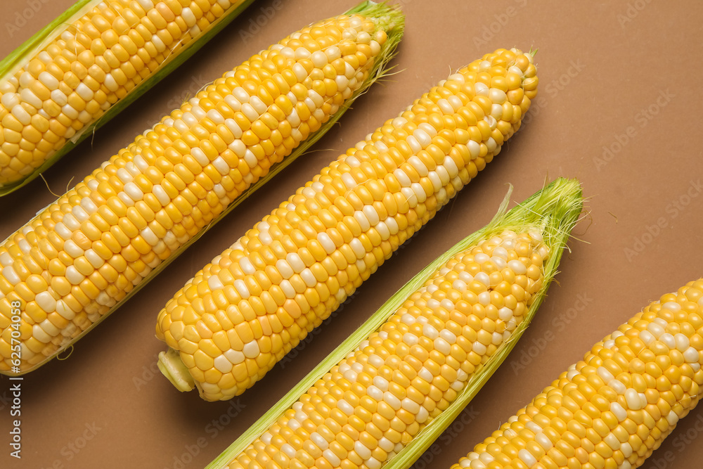 Fresh corn cobs on brown background