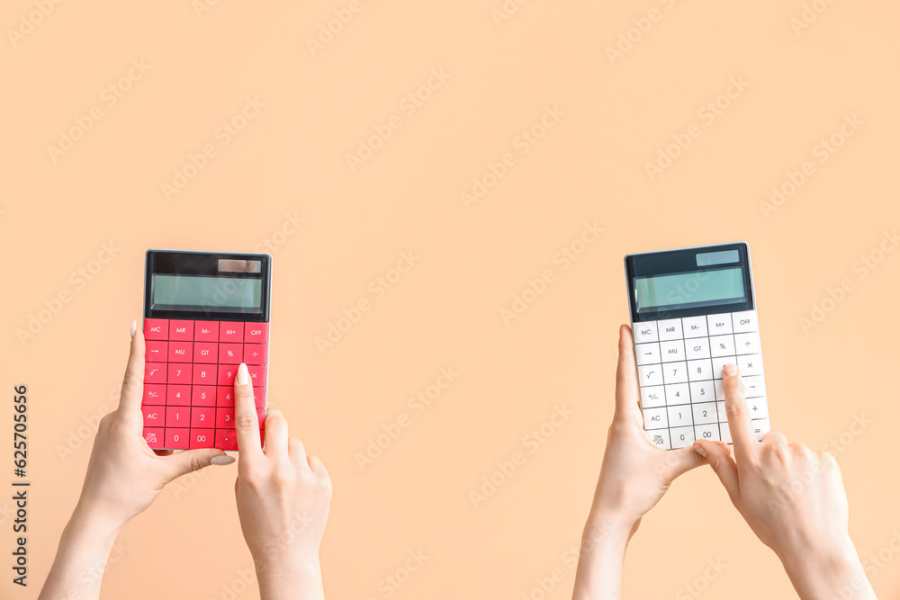 Female hands with calculators on beige background