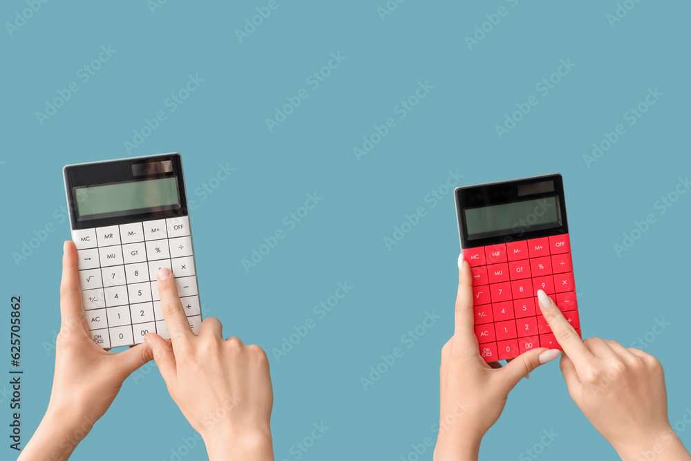 Female hands with calculators on blue background