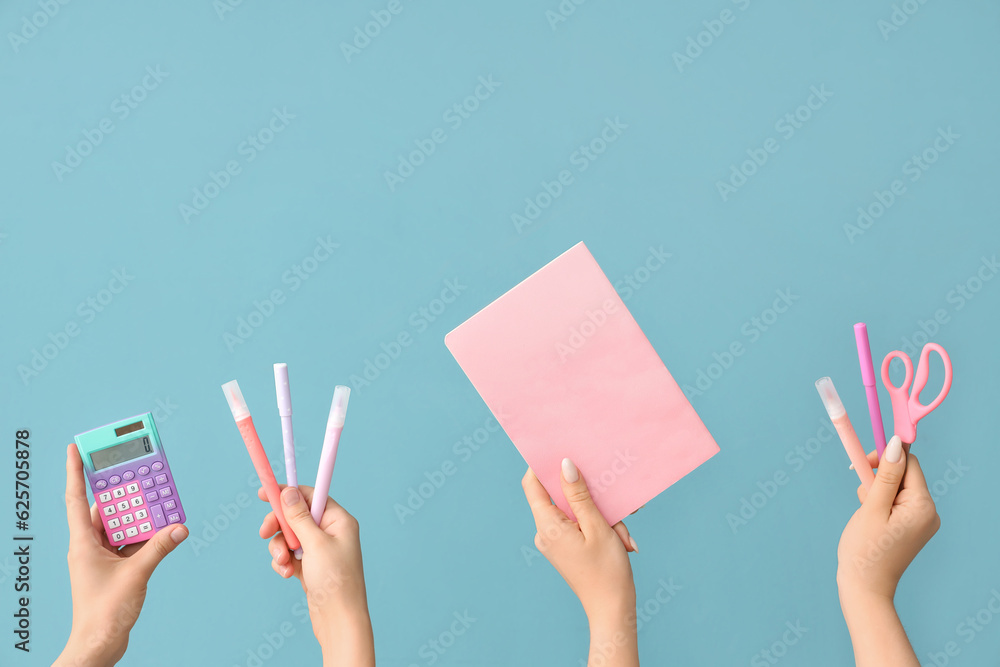 Female hands with school supplies on blue background