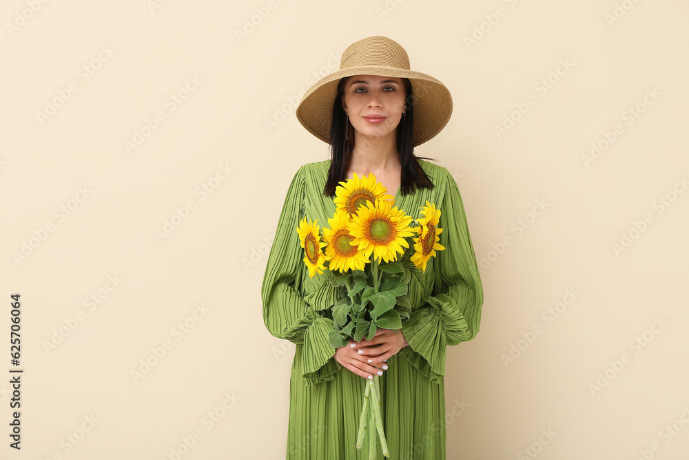 Young woman with beautiful sunflowers on beige background