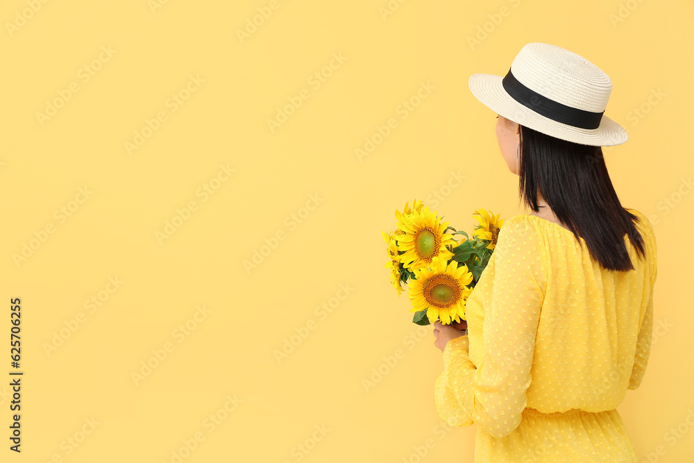 Young woman with beautiful sunflowers on yellow background