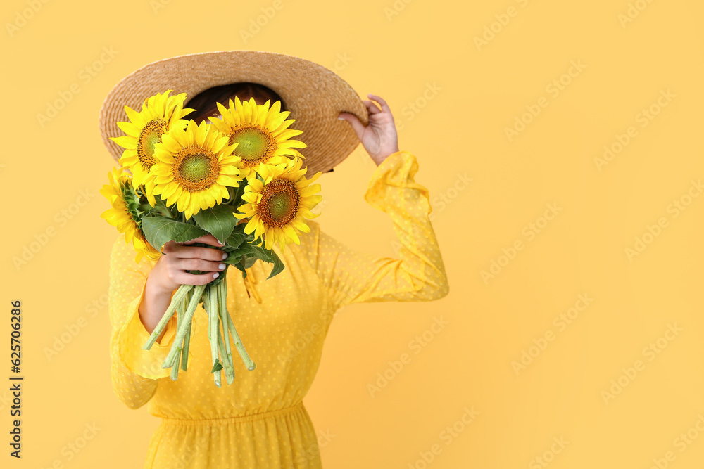 Young woman with beautiful sunflowers on yellow background