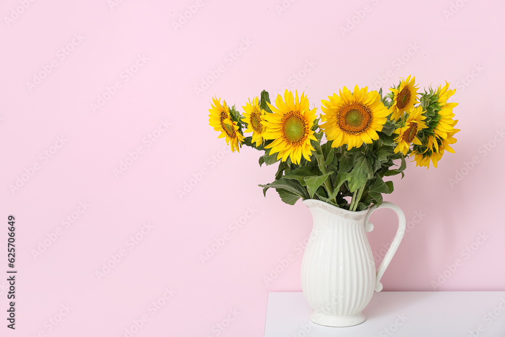 Vase with sunflowers on shelf near pink wall