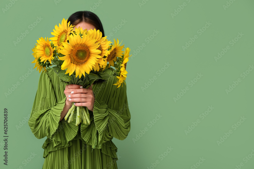 Young woman with beautiful sunflowers on green background