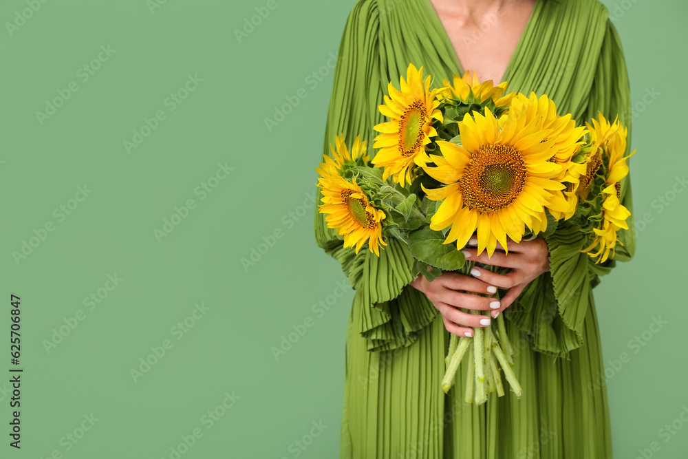 Young woman with beautiful sunflowers on green background