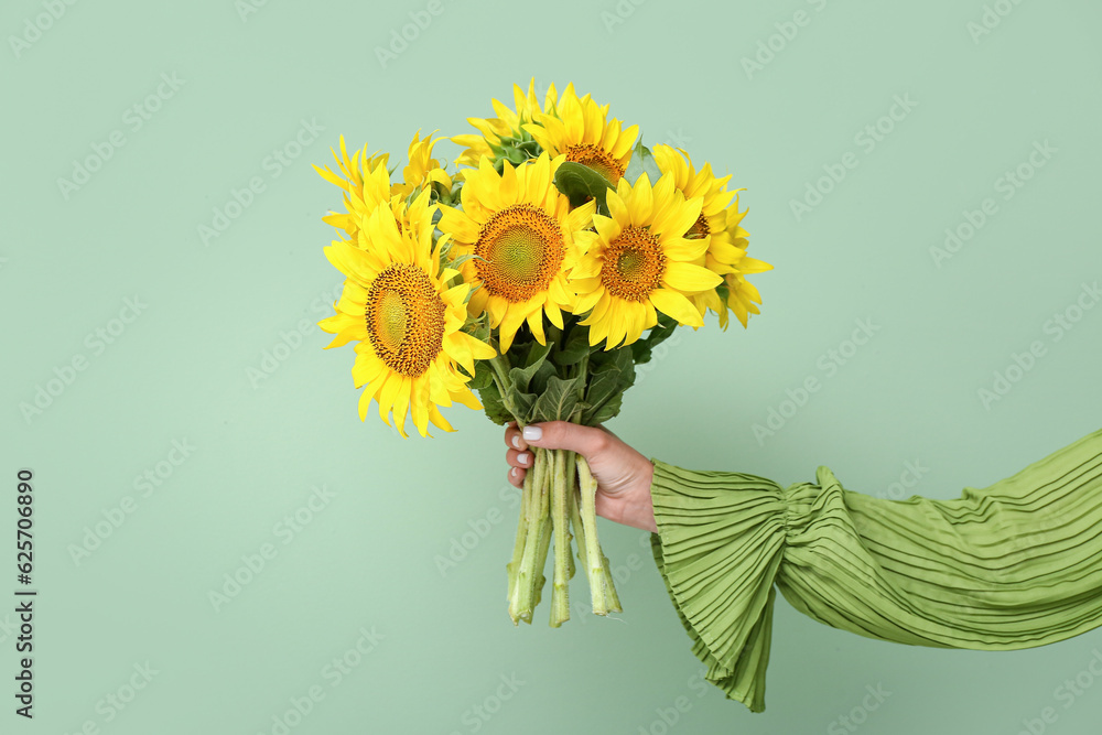 Young woman with beautiful sunflowers on green background