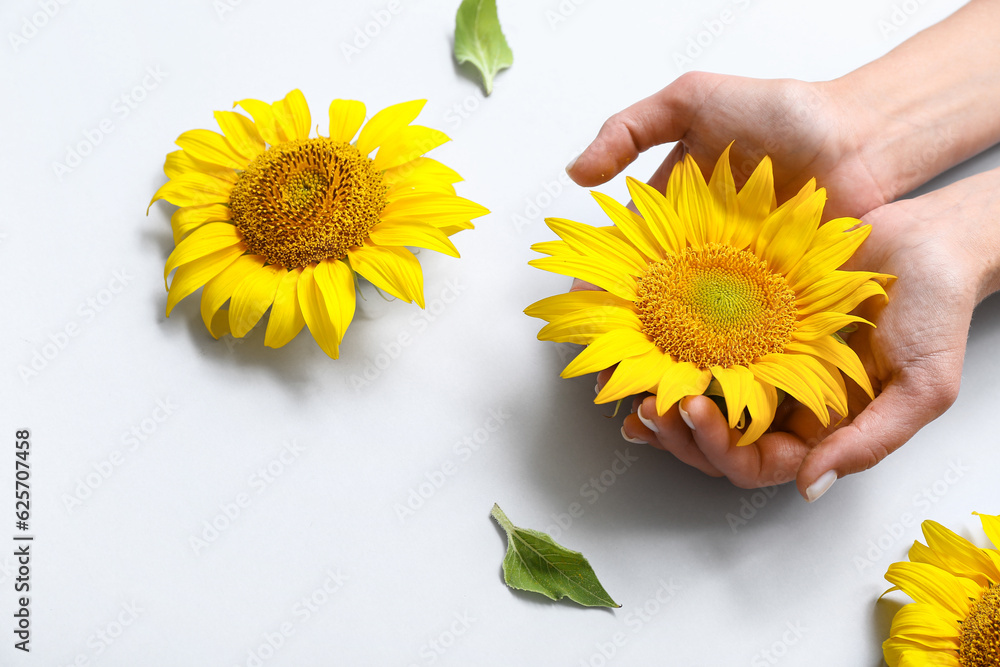 Woman with sunflowers on light background, closeup