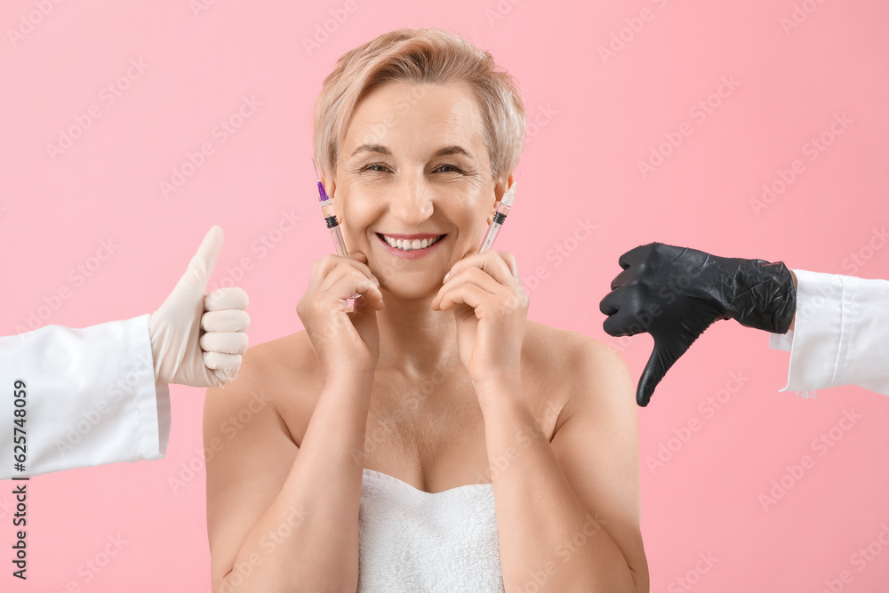 Mature woman with filler injections and gesturing beauticians hands on pink background, closeup