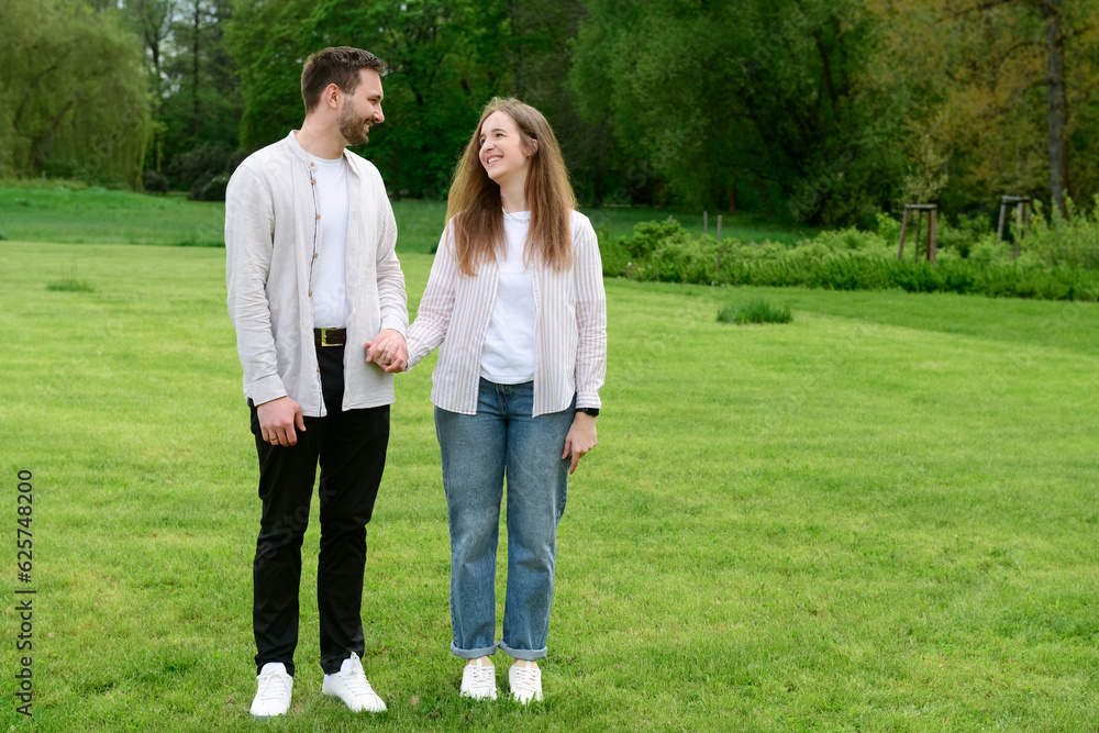 Beautiful loving couple walking in park on spring day