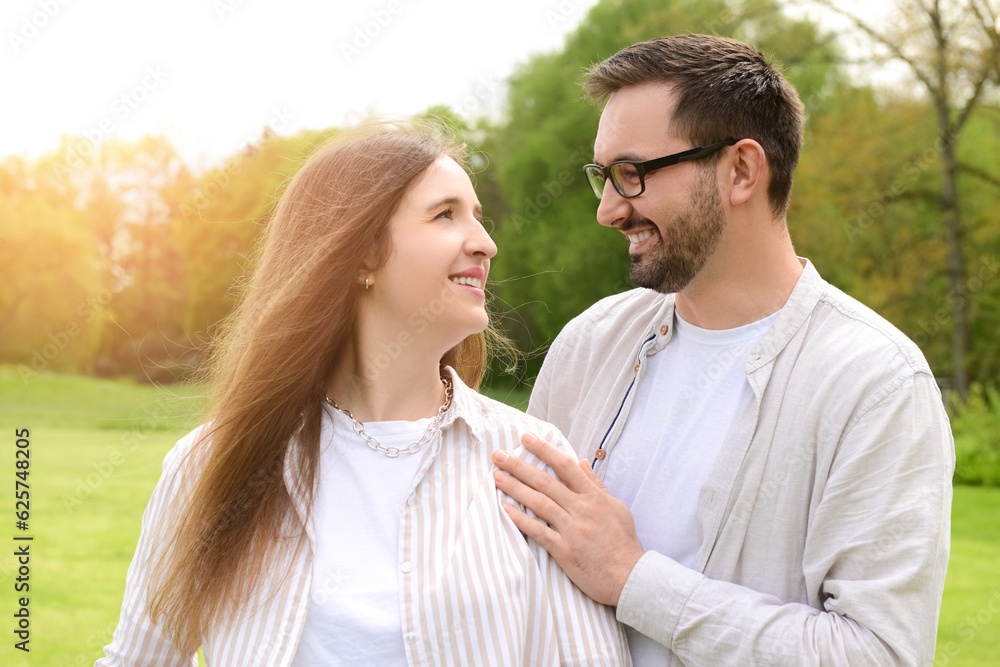 Beautiful happy loving couple hugging and walking in park on spring day