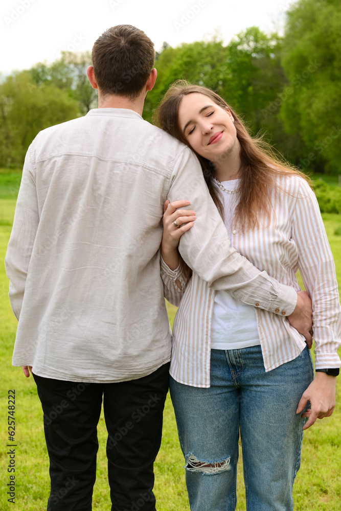 Beautiful happy loving couple hugging and walking in park on spring day